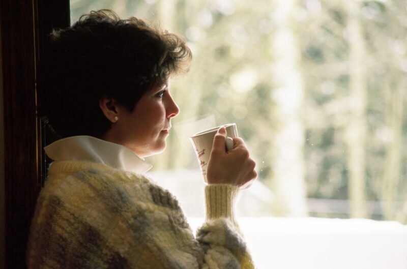 Woman sitting drinking tea looking out the window