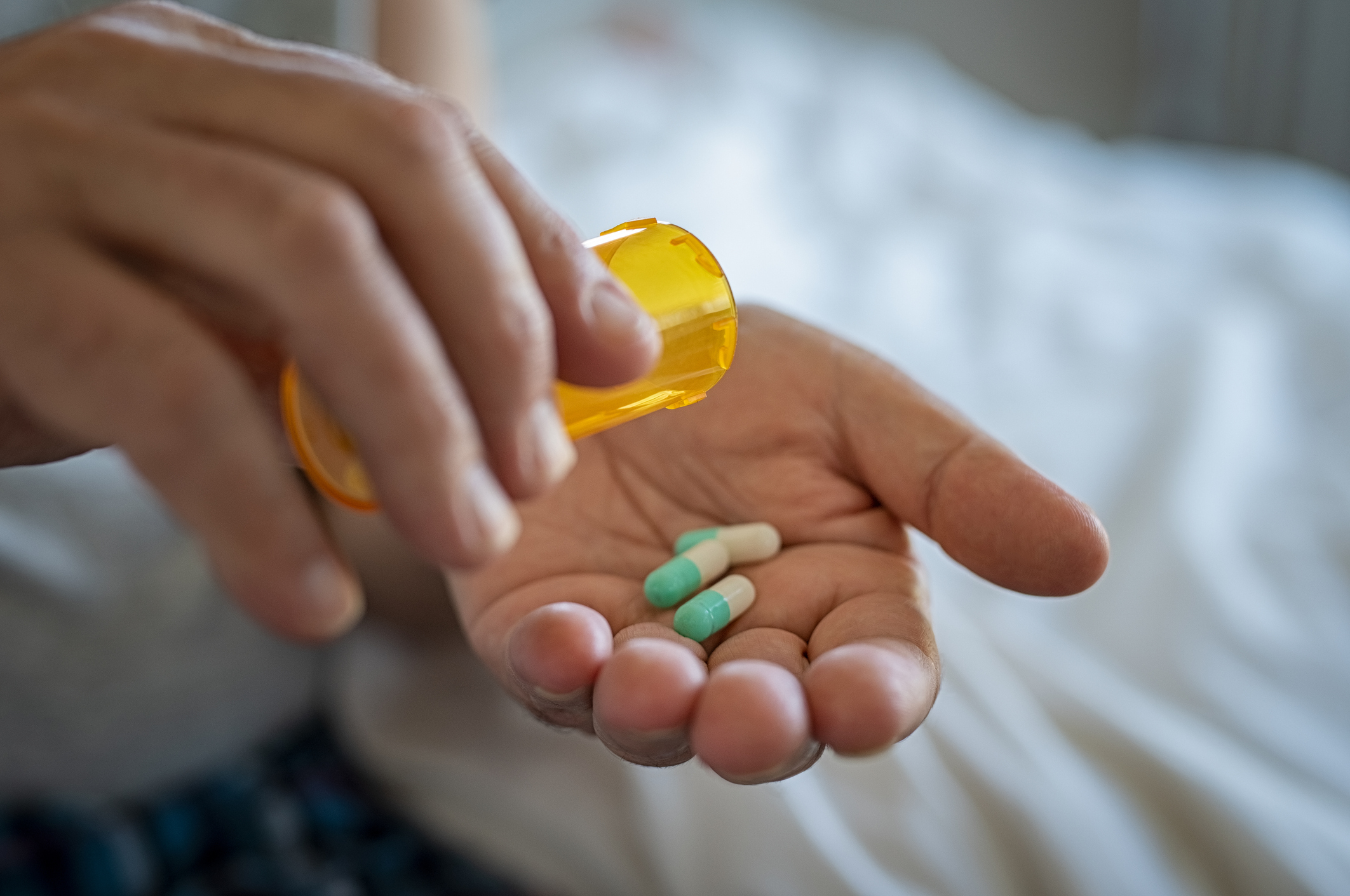 Closeup of man's hand pouring antidepressants from a pill bottle into hand.